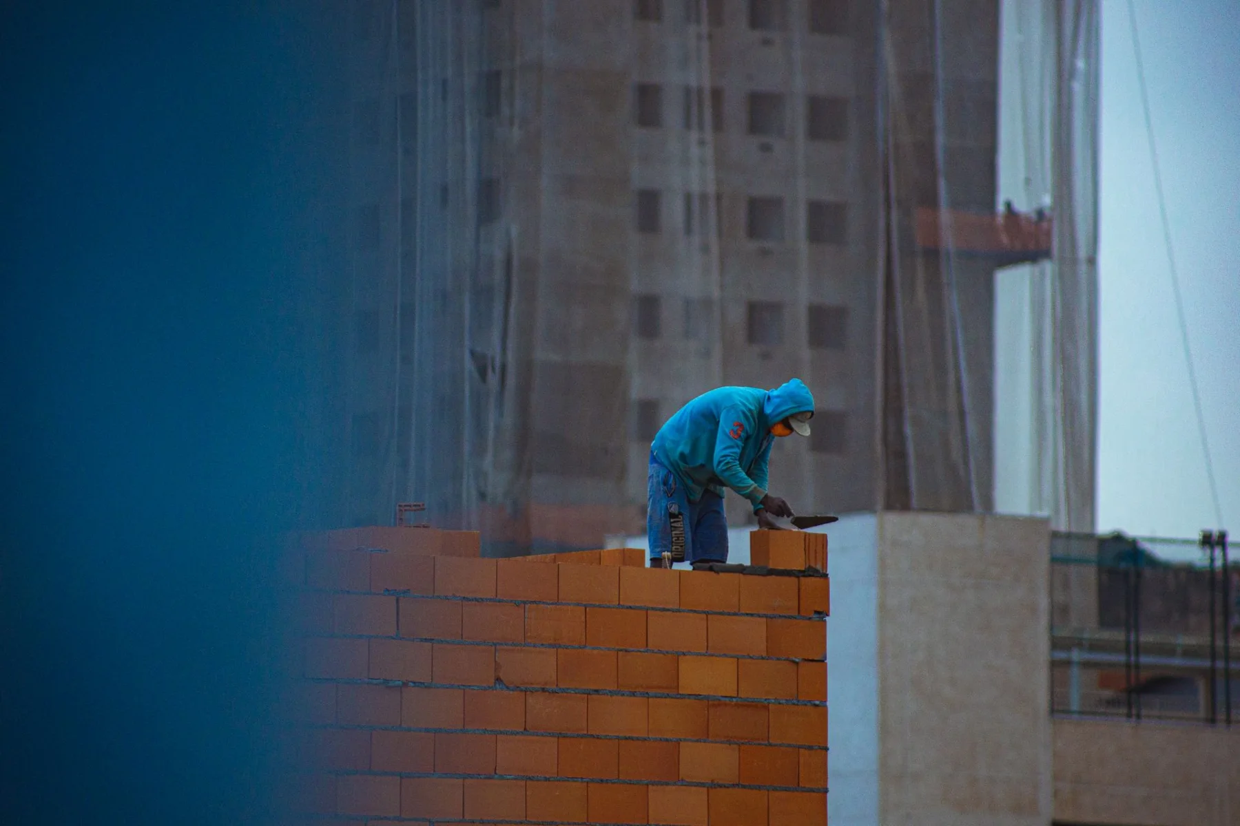 A builder carefully positioning masonry blocks during construction