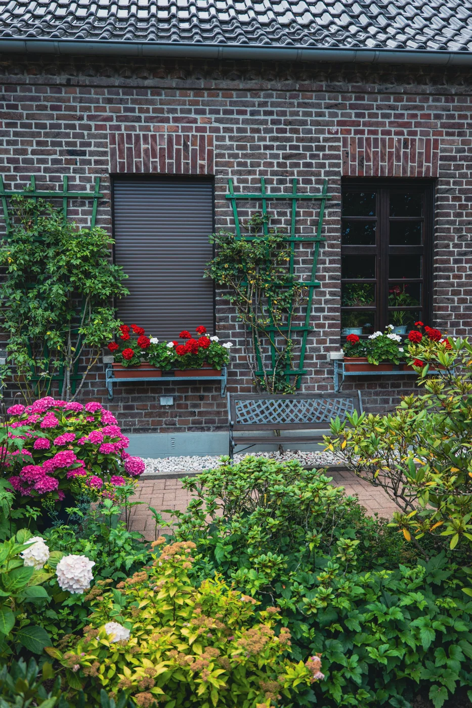 Flowering garden borders beside a traditional brick home